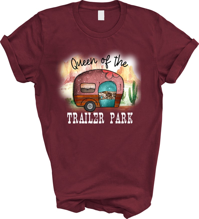 May include: A maroon t-shirt with a graphic of a vintage camper in a desert landscape. The text "Queen of the Trailer Park" is printed below the camper.