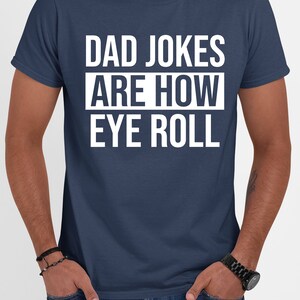 May include: A navy blue t-shirt with white text that reads "Dad Jokes Are How Eye Roll".
