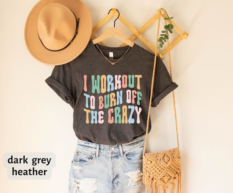 May include: Dark grey heather t-shirt with the text "I workout to burn off the crazy" in colorful letters.