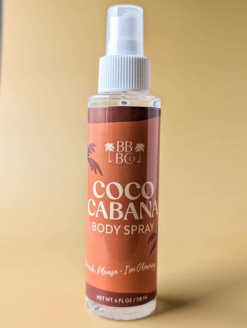 Puede incluir: Un frasco transparente de spray corporal con un pulverizador blanco. La etiqueta es marr&oacute;n con las palabras "COCO CABANA BODY SPRAY" en blanco. La botella contiene 118 ml de producto. El texto "Beach, Please - I'm Glowing" tambi&eacute;n est&aacute; en la etiqueta.