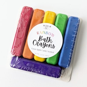 May include: A set of six rainbow bath crayons in a clear plastic package. The crayons are labeled "RAINBOW Bath Crayons" and "Green Apple Candy Scented".