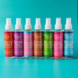 Puede incluir: Siete botellas de spray corporal con boquillas blancas y etiquetas coloridas. Las etiquetas presentan nombres como "Apricot Sunset" y "Ocean Aire" con un gr&aacute;fico de palmera. Cada botella contiene 118 ml.