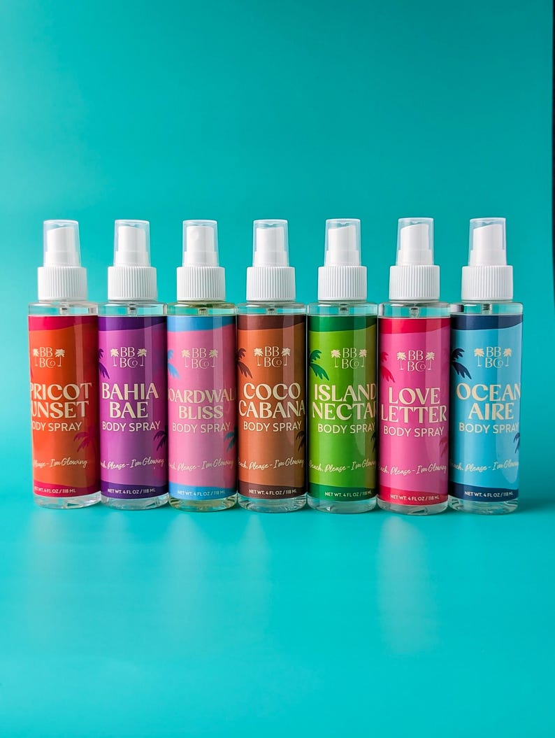 Puede incluir: Siete botellas de spray corporal con boquillas blancas y etiquetas coloridas. Las etiquetas presentan nombres como "Apricot Sunset" y "Ocean Aire" con un gr&aacute;fico de palmera. Cada botella contiene 118 ml.