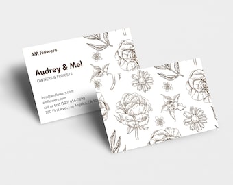 May include: Business card for AM Flowers, owned by Audrey & Mel. The card features a white background with a floral pattern in brown ink. The business name, owners' names, contact information, and address are printed in brown ink.
