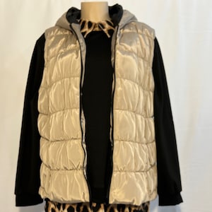 May include: A beige puffer vest with a black hooded sweatshirt and a leopard print shirt underneath.