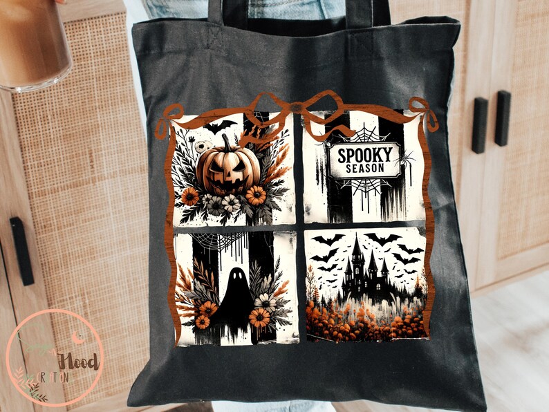 May include: Black tote bag featuring a Halloween-themed design. The design includes a jack-o'-lantern, a ghost, a haunted house, and the words "Spooky Season". The artwork is framed with a brown border and includes bats.