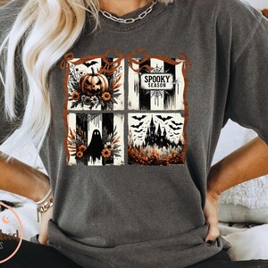 May include: Dark gray t-shirt featuring a four-panel Halloween design. The panels include a jack-o'-lantern, the text "Spooky Season", a ghost, and a haunted castle. The design incorporates black, orange, and white elements.