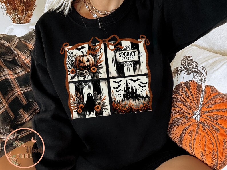 May include: Black sweatshirt featuring a four-panel Halloween design. The panels include a jack-o'-lantern, a ghost, a haunted house, and the words "Spooky Season". The design is framed with a brown border.