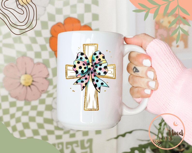 May include: White ceramic coffee mug with a gold cross and a colorful polka dot bow. The bow is pink, blue, and yellow with black polka dots.
