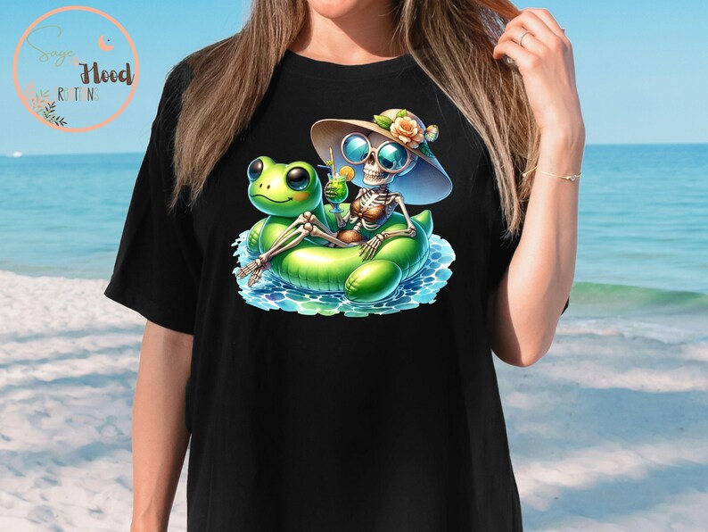 Może przedstawiać: Czarny T-shirt z grafiką przedstawiającą szkielet w kapeluszu przeciwsłonecznym i okularach przeciwsłonecznych, pływający na zielonej dmuchanej żabie. Szkielet trzyma zielony koktajl.