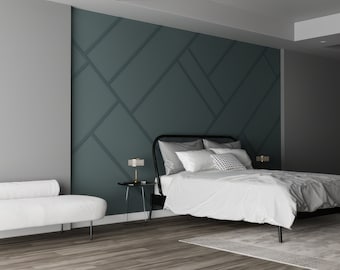 May include: A white bed with a gray blanket and white pillows sits in a bedroom with a teal and gray geometric wall. A white couch with a rolled back sits in the foreground.