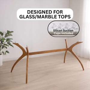 Könnte beinhalten: Ein Tischgestell aus Holz mit vier geschwungenen Beinen und einem Mittelsteg. Der Text DESIGNED FOR GLASS/MARBLE TOPS steht darüber. Ein kleiner Einschub zeigt vier enthaltene, transparente Silikon-Saugnäpfe zur Befestigung der Tischplatte.