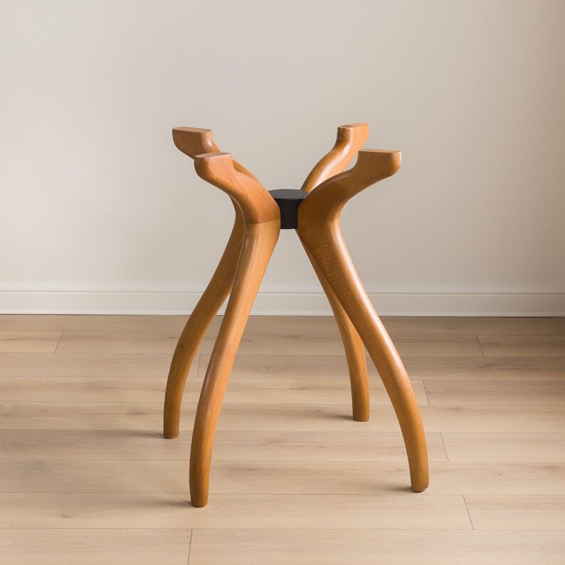 May include: A wooden table base with four curved legs and a black center support. The legs are a light brown color and have a smooth finish. The base is designed to support a tabletop and is suitable for a dining or coffee table.