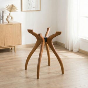 May include: A wooden table base with six curved legs. The legs are a warm brown colour and extend outwards from a central black support. The table base is designed for a modern aesthetic.