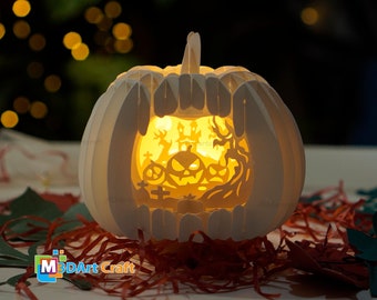 Może przedstawiać: Biała papierowa dynia z włączonym światłem. Dynia jest wycięta, aby odsłonić straszną scenę Halloweenową z nawiedzonym domem, drzewami i dyniami.