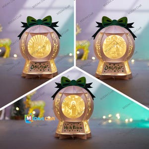 Könnte beinhalten: Eine Papier-Weihnachts- oder Osterlaterne mit kugelförmigem Design. Die Laterne hat eine grüne Schleife und ein schwarzes Band oben. Der Sockel trägt den Text "O Holy Night" oder "He Is Risen". Die Innenszene ist beleuchtet.