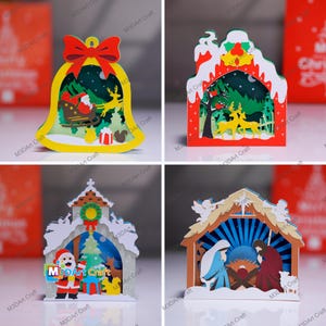 May include: Four layered paper Christmas decorations. Designs include a bell with Santa and reindeer, a red house with deer, a church with Santa, and a nativity scene. The ornaments are made by M3DArt Craft.