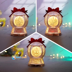 Puede incluir: Una linterna navideña decorativa con un diseño esférico. La linterna presenta una escena de bosque recortada iluminada desde el interior, un lazo rojo y el texto "Merry Christmas". La linterna está hecha de papel beige y es adecuada para la decoración navideña.