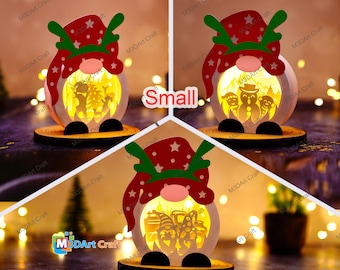 Pode incluir: Pequena decoração de gnomo de Natal iluminada. O gnomo tem um chapéu vermelho com estrelas brancas e chifres verdes. O corpo é uma esfera branca com um design recortado, e a base é um disco de madeira. A palavra "Small" é visível.