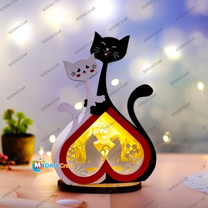 May include: A wooden heart-shaped lamp with a cutout design of two cats and the words "My Love". The lamp is lit up, casting a warm glow.