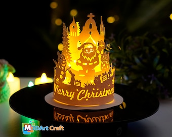 Könnte beinhalten: Beleuchtete Papier-Weihnachtsdekoration mit festlichem Design. Das Design umfasst den Weihnachtsmann, einen Schneemann und den Schriftzug "Merry Christmas". Die Dekoration steht auf einem schwarzen Ständer und strahlt warmes Licht aus.