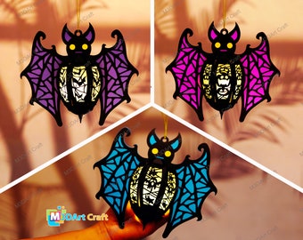May include: Three hanging bat ornaments with intricate cut-out designs. The bats are purple, pink, and blue with a white glow in the center. The bats are hanging from a string.