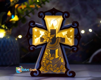 May include: A wooden cross with a 3D layered design. The cross is illuminated from behind, creating a glowing effect. The design features a dove, flowers, and a mountain scene.