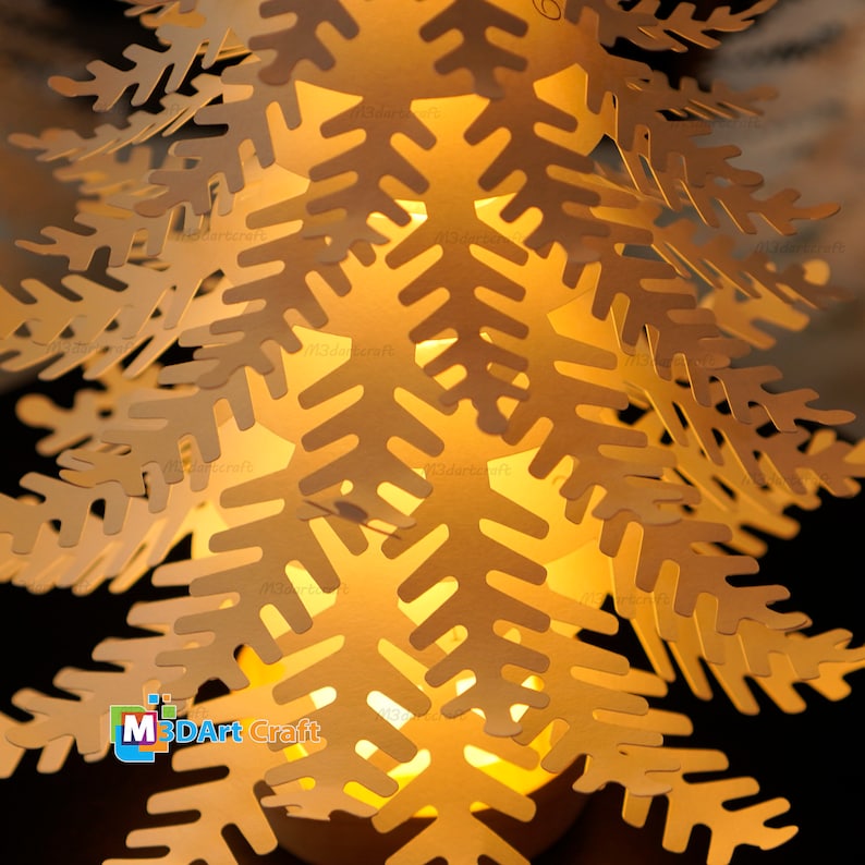 Peut inclure: Un arbre de No&euml;l en papier avec une lumi&egrave;re &agrave; l'int&eacute;rieur, compos&eacute; de flocons de neige superpos&eacute;s. L'arbre est &eacute;clair&eacute; de l'int&eacute;rieur, projetant une lueur chaude. L'arbre est en papier blanc et pr&eacute;sente un design d&eacute;licat et complexe.