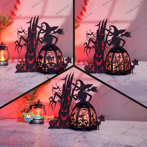 Op de afbeelding: Een zwarte metalen Halloween-kaarshouder met een heks, een boom en vleermuizen. De kaarshouder is aangestoken en gloeit oranje.