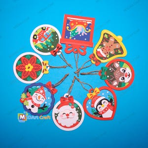 May include: A collection of eight colorful Christmas ornaments featuring festive designs including a snowman, Santa Claus, a penguin, a reindeer, a poinsettia, a gingerbread man, a sleigh, and a truck, each with a small jute twine hanging loop.