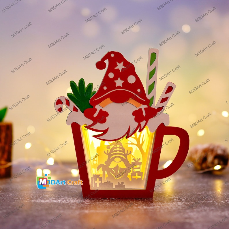 K&ouml;nnte beinhalten: Eine rote und wei&szlig;e Holzfigur eines Weihnachtsgnoms, die einen Zuckerstock h&auml;lt und in einer roten Tasse mit wei&szlig;em Innenraum steht. Die Tasse hat einen Henkel und ein Licht im Inneren. Der Gnom hat einen wei&szlig;en Bart und eine rote M&uuml;tze mit einem wei&szlig;en Stern.