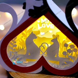May include: A white and red heart-shaped wooden box with a light inside. The box has a cutout design of two cats sitting on a bench with a heart between them. The text "My Love" is visible in the center of the box.