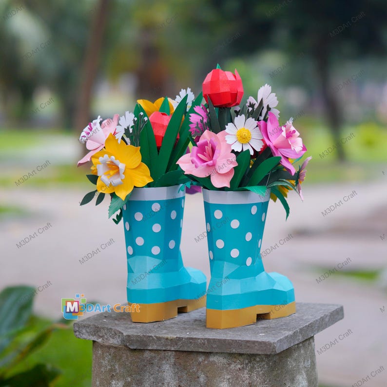 May include: Two papercraft flower arrangements in turquoise polka-dot rain boots. The boots have yellow soles and white trim. The flowers include yellow daffodils, pink roses, and a red tulip. The background is blurred.