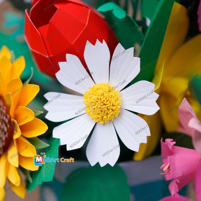 May include: A close-up of a paper flower arrangement featuring a large white daisy with a yellow center, a red tulip, and a yellow sunflower. The arrangement is colorful and detailed, with visible papercrafting techniques.