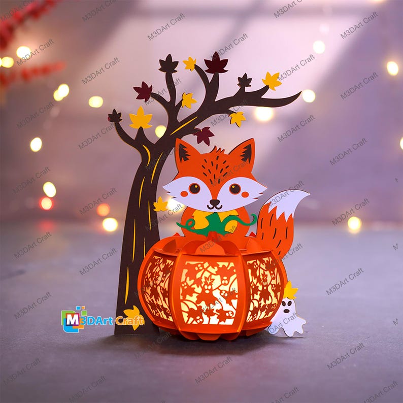 May include: A layered paper craft featuring a cartoon fox sitting atop an orange pumpkin lantern. A tree with fall leaves and a small ghost are also included. The text "M3DArt Craft" is visible. The overall theme is autumn and Halloween.