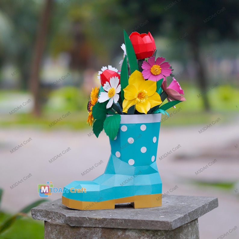 May include: A turquoise paper boot with white polka dots holds a colorful paper flower arrangement. The flowers include red tulips, yellow daffodils, and pink daisies. The boot has a gold-colored sole and is sitting on a stone surface.