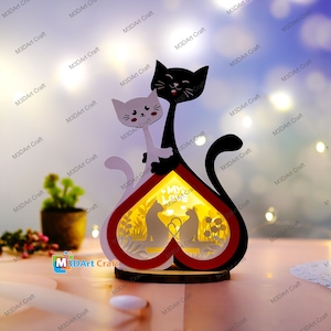 May include: A wooden heart-shaped night light with a black and white cat design. The heart is illuminated with a warm glow and features the text "My Love" inside. The cats are holding each other and have a sweet expression on their faces.