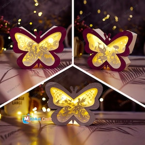 Puede incluir: Tres lámparas de papel en forma de mariposa iluminadas con diseños intrincados. Las mariposas son en tonos de morado, gris y marrón. Cada mariposa tiene un hada y flores dentro de las alas.