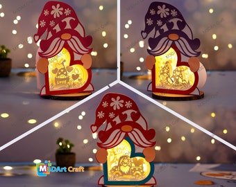 Pode incluir: Três luzes noturnas de madeira em forma de gnomo com uma janela em forma de coração. Cada gnomo tem um chapéu de uma cor diferente: vermelho, roxo e rosa. A janela em forma de coração mostra uma cena com um casal de gnomos e a palavra "LOVE".