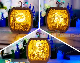 以下が含まれることがあります： 複雑なハロウィーンのシーンが描かれた、光るペーパークラフトのジャック・オ・ランタン3つ。ジャック・オ・ランタンは白で、黄色く光っており、墓地、魔女、幽霊屋敷など、不気味なディテールが描かれています。