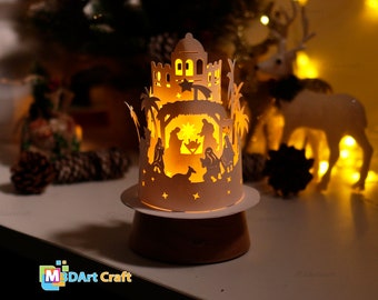 May include: A white paper Christmas nativity scene light-up with a cutout design of the nativity scene, palm trees, and a star. The light-up is on a wooden base and is lit with a warm white light.