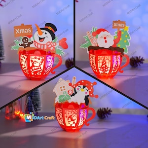 May include: Three red paper Christmas light-up mugs with different holiday characters. The first mug features a snowman with a red hat and scarf. The second mug features Santa Claus with a red hat and beard. The third mug features a penguin with a red hat and scarf. Each mug has a "Xmas" sign.