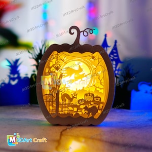 May include: A white papercraft pumpkin with a Halloween scene inside. The scene includes a moon, a spider web, a cat, a fence, and a spooky tree. The pumpkin is lit from inside, creating a warm glow.