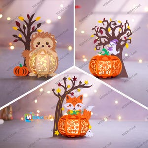 May include: A collection of three Halloween-themed paper lanterns. Each lantern features a carved pumpkin design with a tree and a woodland creature: a hedgehog, a ghost, and a fox. The lanterns are illuminated, creating a warm glow.