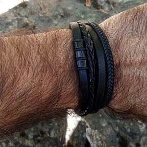 Peut inclure: Un bracelet en cuir noir avec un design tressé et des accents métalliques.