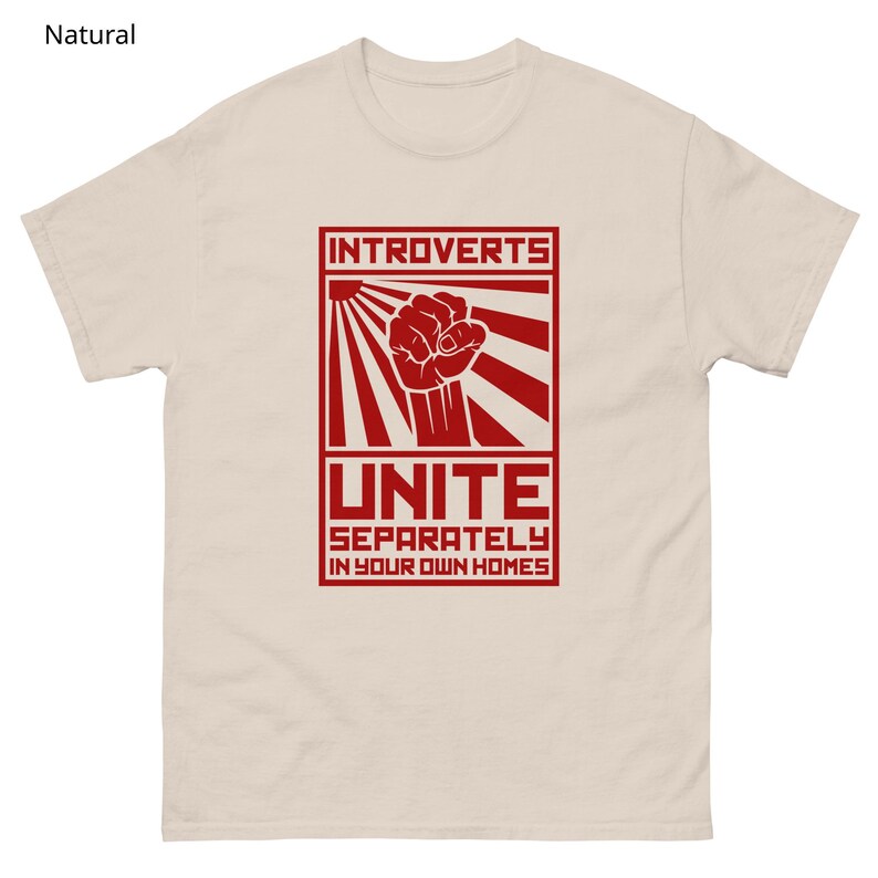 May include: A natural-colored t-shirt with a red graphic. The graphic features the word "INTROVERTS" above a clenched fist, rays, and the word "UNITE" with the phrase "SEPARATELY IN YOUR OWN HOMES" below.