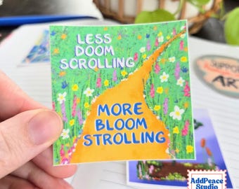 May include: A square sticker featuring a vibrant green meadow filled with colorful wildflowers and a winding orange path. The text reads LESS DOOM SCROLLING in white and MORE BLOOM STROLLING in blue, set against the illustrated landscape.
