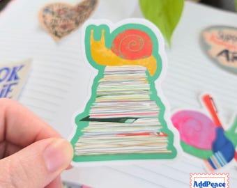 May include: A die-cut sticker featuring a yellow snail with a red shell perched atop a tall, vertical stack of white papers. The entire illustration is framed by a solid green border, creating a distinct shape that highlights the snail and the paper pile.