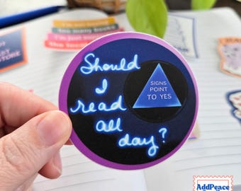 May include: A circular sticker with a dark background featuring neon blue cursive text that reads Should I read all day? and a blue triangle graphic containing the white text SIGNS POINT TO YES, all bordered by a thin purple outline.