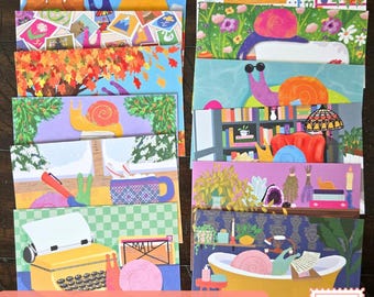 May include: A set of illustrated postcards featuring various scenes with colourful snails. Designs include snails in autumn leaves, a library, a bathtub, a garden, a snowy window, and a yellow typewriter. Each card displays unique, vibrant artwork.